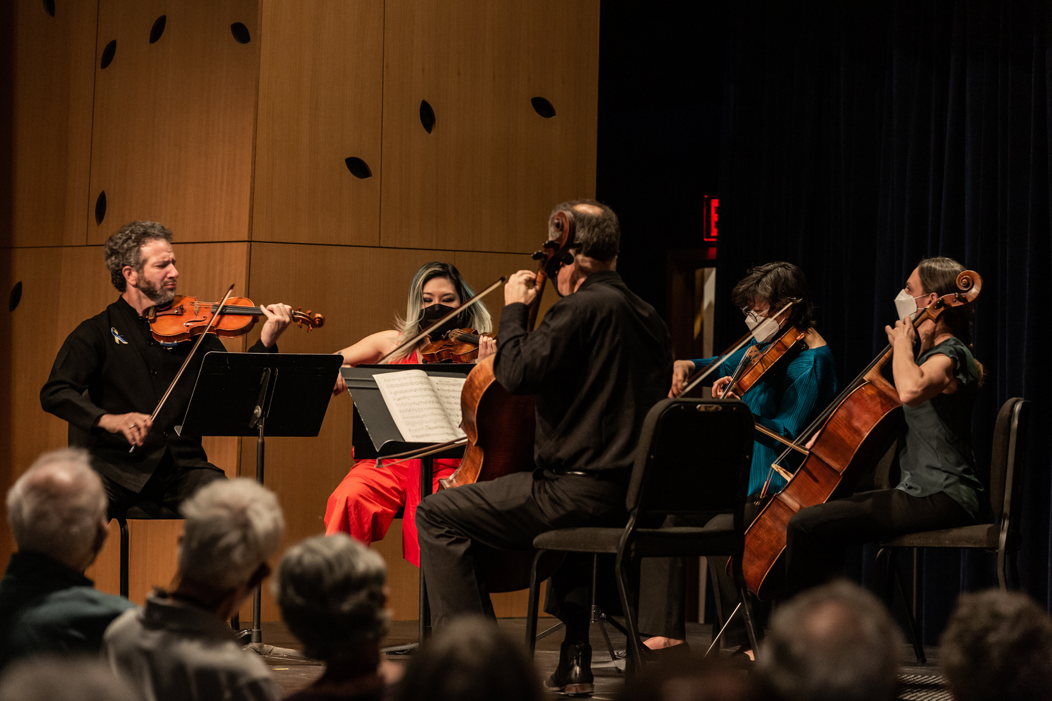 Close up of two violinists, a violist, and two cellists performing on stage.