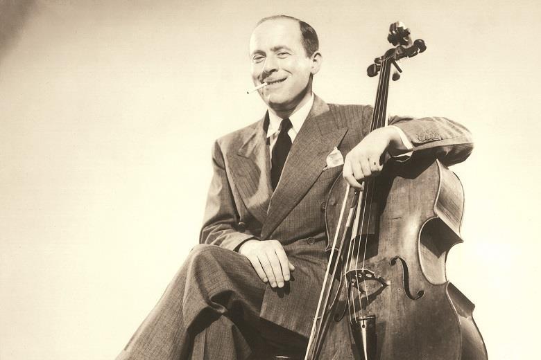 Emanuel Feuermann sitting with his left arm around the neck of his cello and a cigarette hanging between his lips